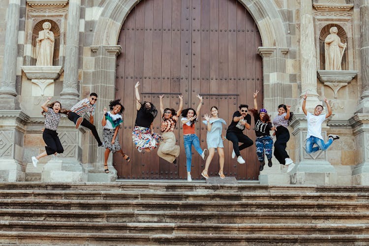 Photo Of People Jumping In Front Of Entrance Door To A Building