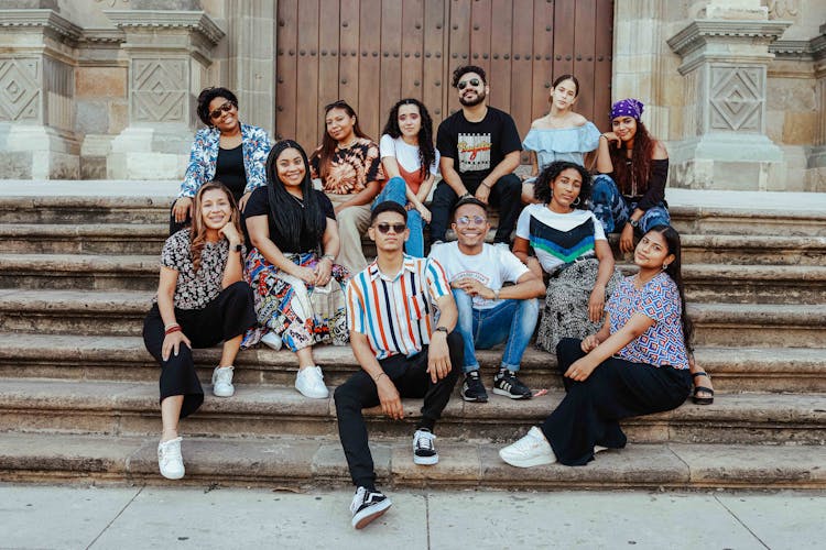 A Group Of People Sitting On Concrete Stairs