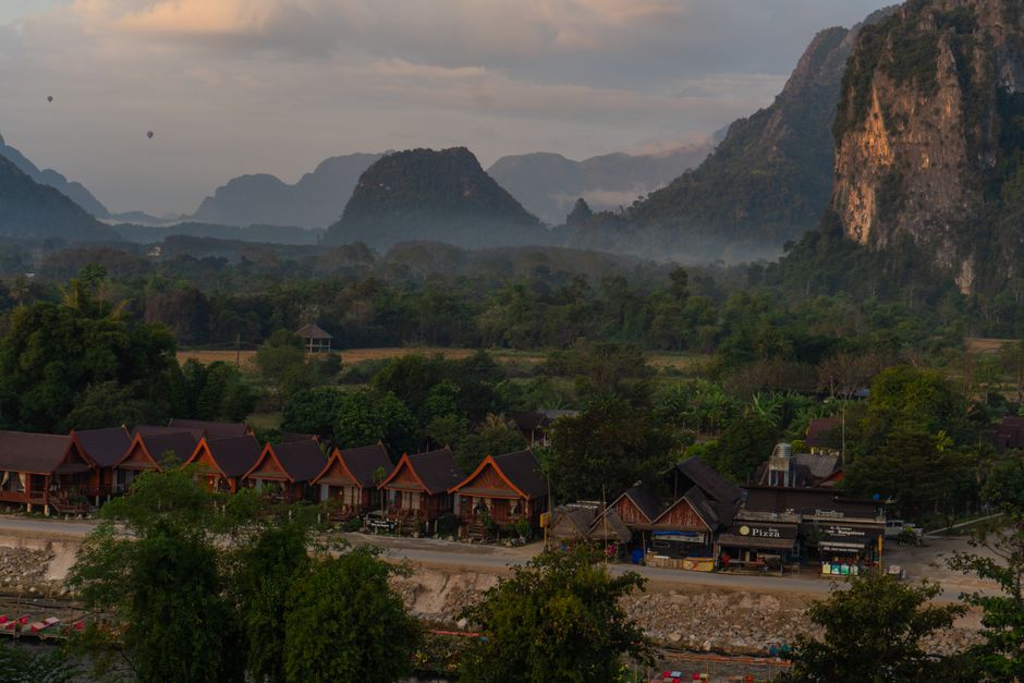 Calming landscape view of Vang Vieng, Laos, showcasing huts, mountains, and misty scenery.