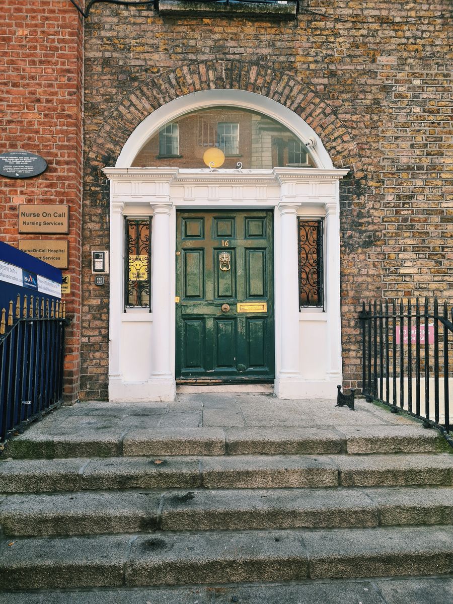 A green Georgian door between columns on a Dublin brick facade