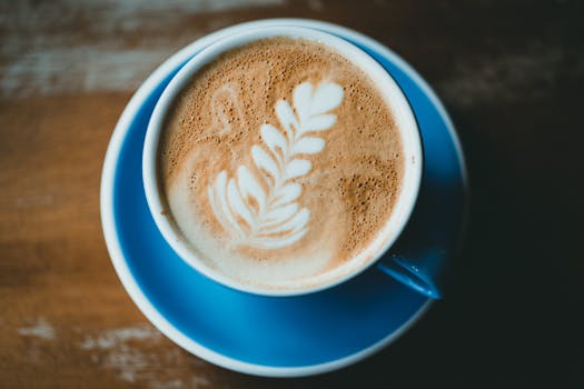 A beautifully crafted latte art design in a cup, set on a blue saucer for a perfect coffee moment.