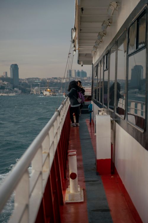 Free Two adults standing on a ferry deck enjoying views of the city skyline over water. Stock Photo