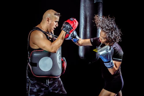 Woman Punching the Hand of Man Wearing Training Gloves