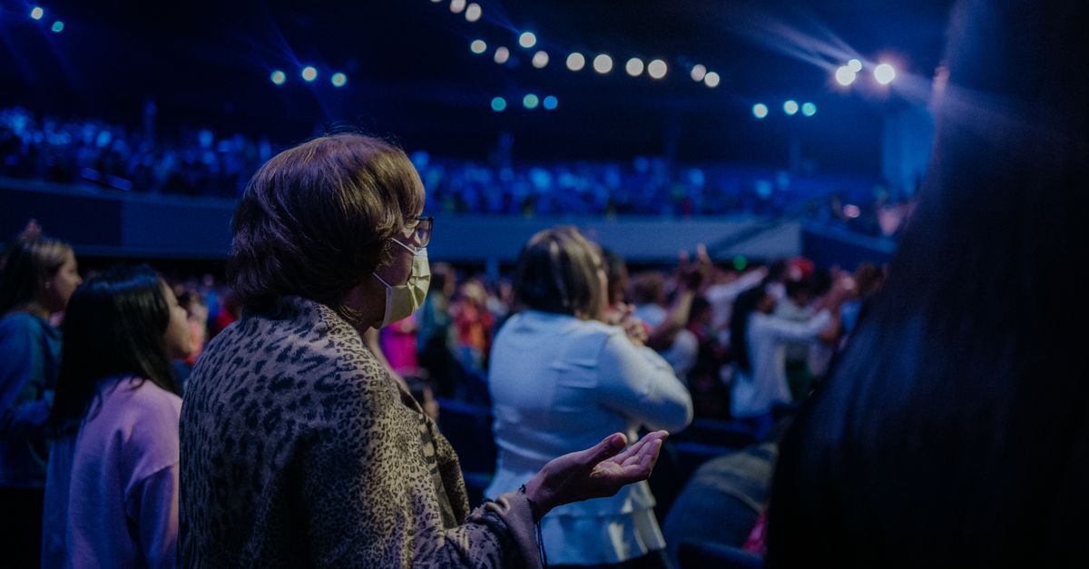 Congregation at Christ Embassy Ho raising hands during Friday night worship with stage lights