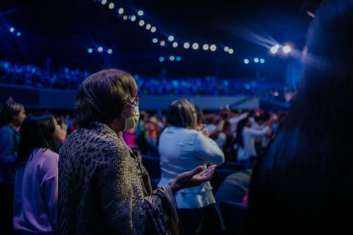 Free A spiritual gathering with people praying and worshiping under bright indoor lights. Stock Photo