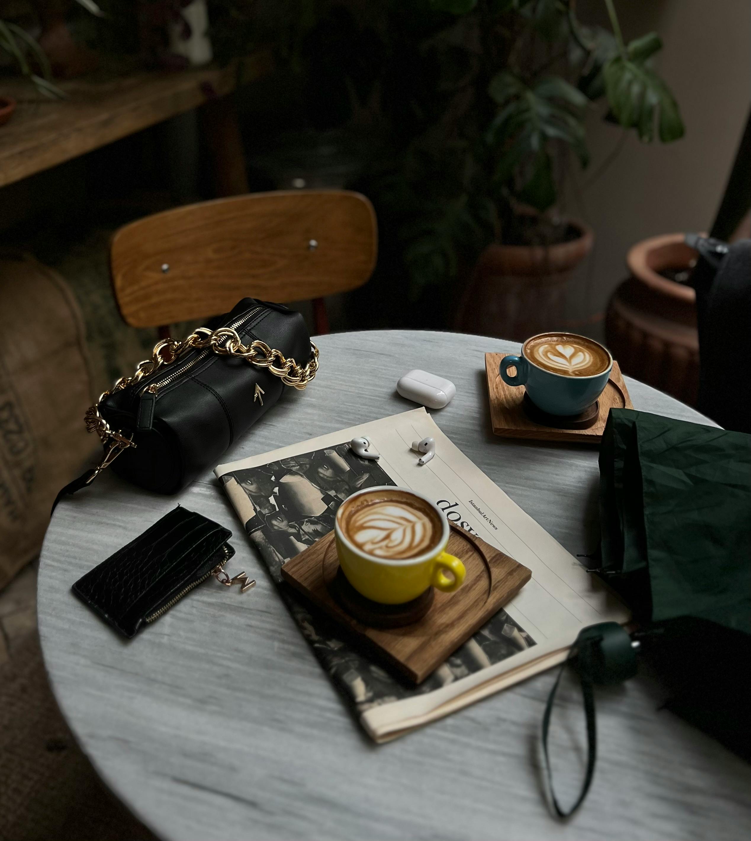 Aerial view of two cappuccinos on a table in a cozy coffee shop setting with accessories.