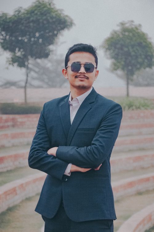 Free Confident man in a suit and sunglasses poses in an outdoor park setting in Dhaka. Stock Photo