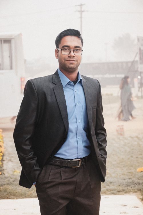 Free Stylish man in black suit posing confidently outdoors with a foggy background. Stock Photo
