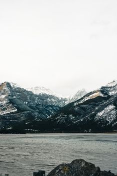 Captivating winter view of snow-capped mountains in Jasper, Alberta, Canada, across a serene lake.