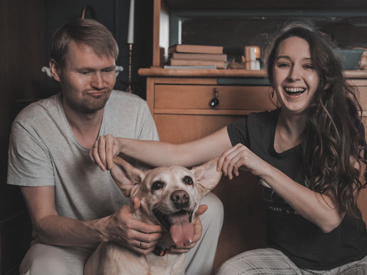 Joyful couple playing with their dog indoors at home
