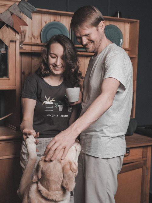 Free A joyful couple bonding with their golden retriever dog indoors. Stock Photo