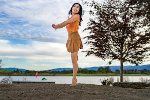 Young Woman in a Skirt Dancing by a Body of Water 