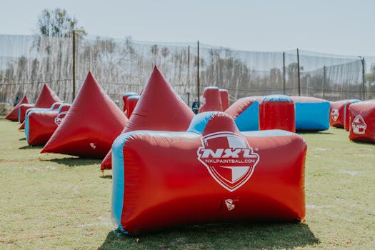 Bright paintball field with red and blue inflatable obstacles set up for an exciting game.