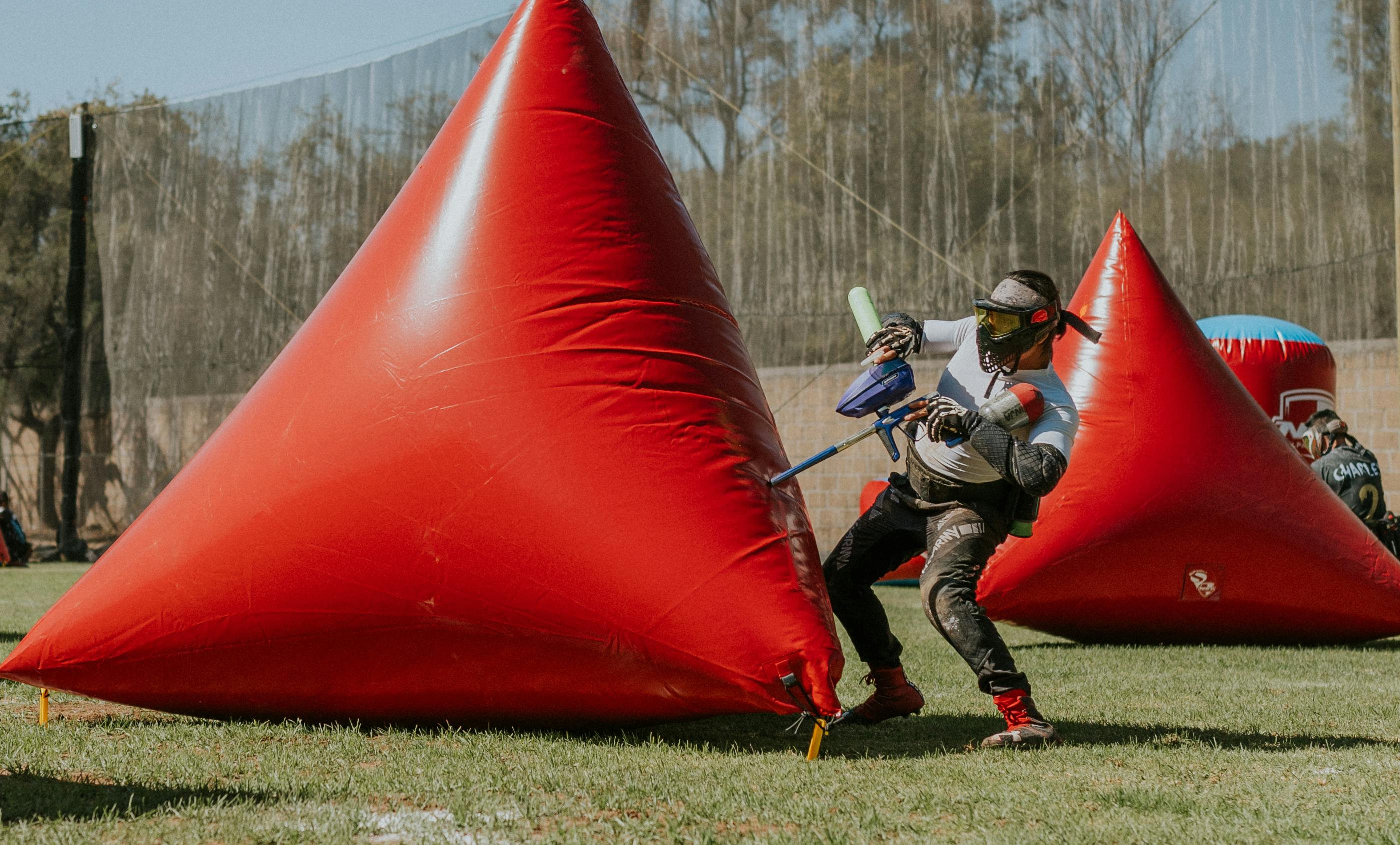 Player tactically navigating paintball field with inflatable bunkers. Prescription Goggle Inserts - Player tactically navigating paintball field with inflatable bunkers.