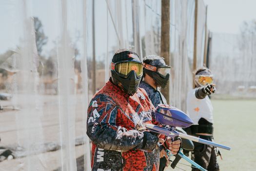 Group of adults playing paintball in vibrant gear, showcasing teamwork and sport.