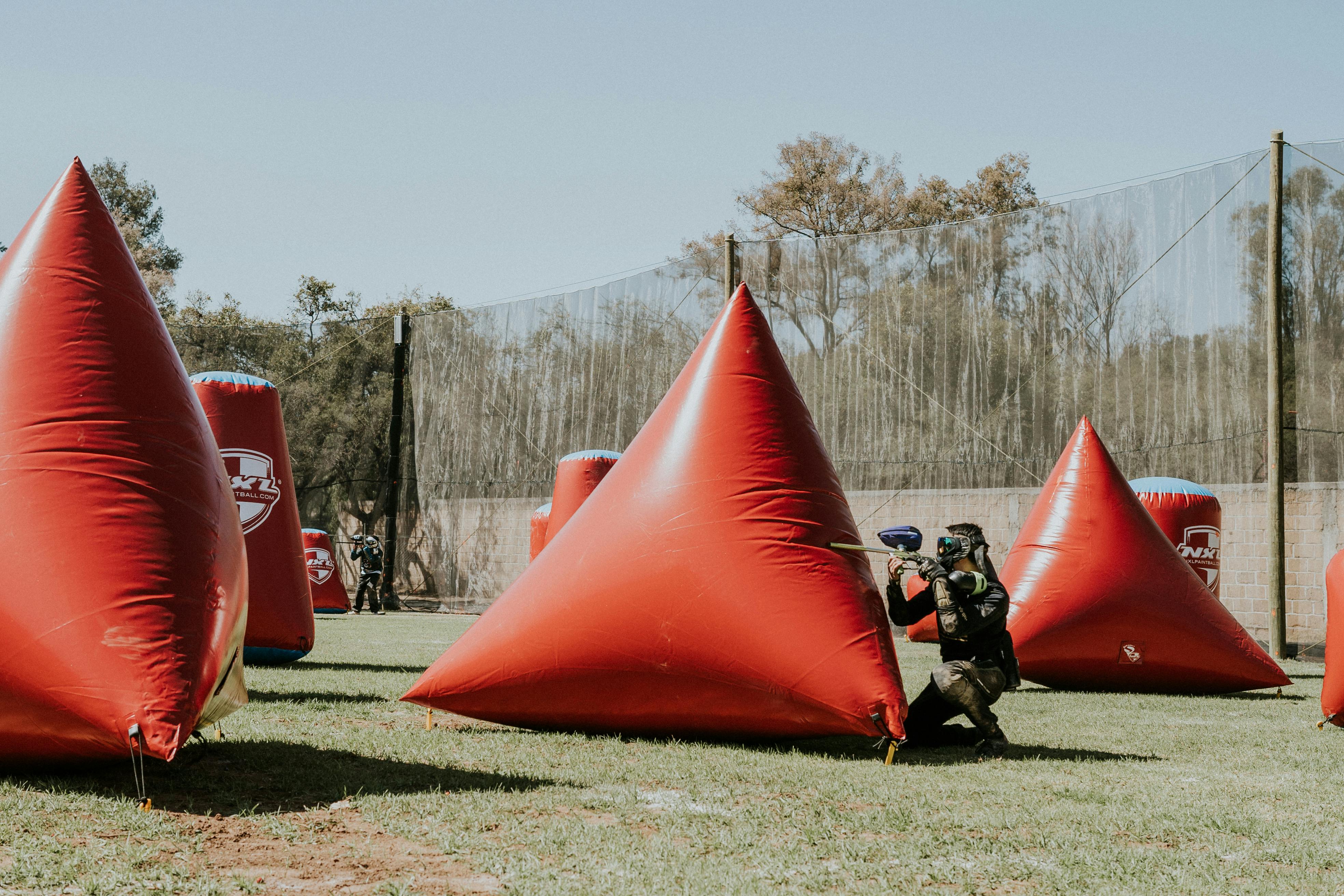 Dynamic outdoor paintball game with participants aiming and hiding behind inflatable barriers. Prescription Goggle Inserts - Dynamic outdoor paintball game with participants aiming and hiding behind inflatable barriers.