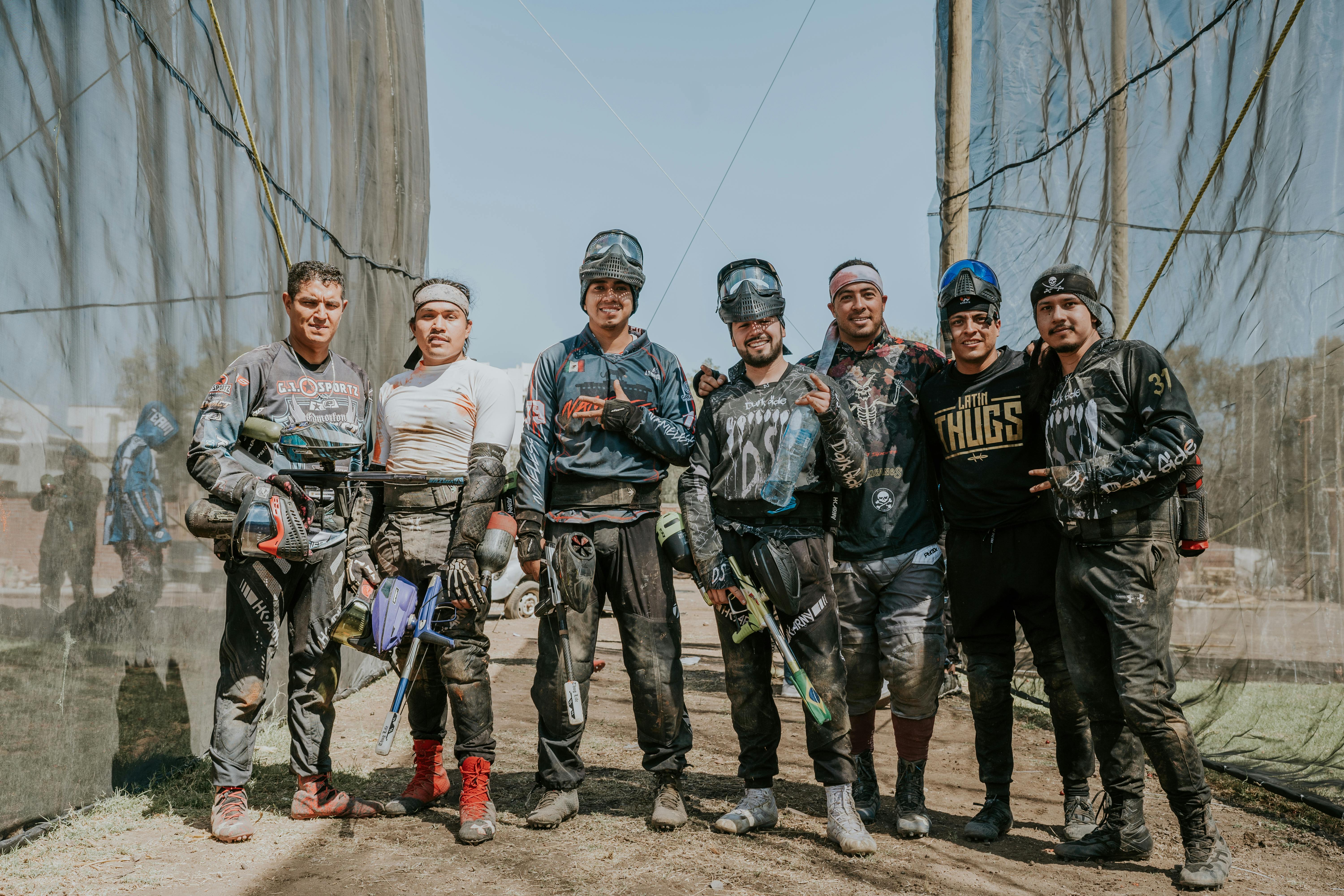 A team of men in paintball gear posing outdoors with smiles and paint markers. Prescription Goggle Inserts - A team of men in paintball gear posing outdoors with smiles and paint markers.