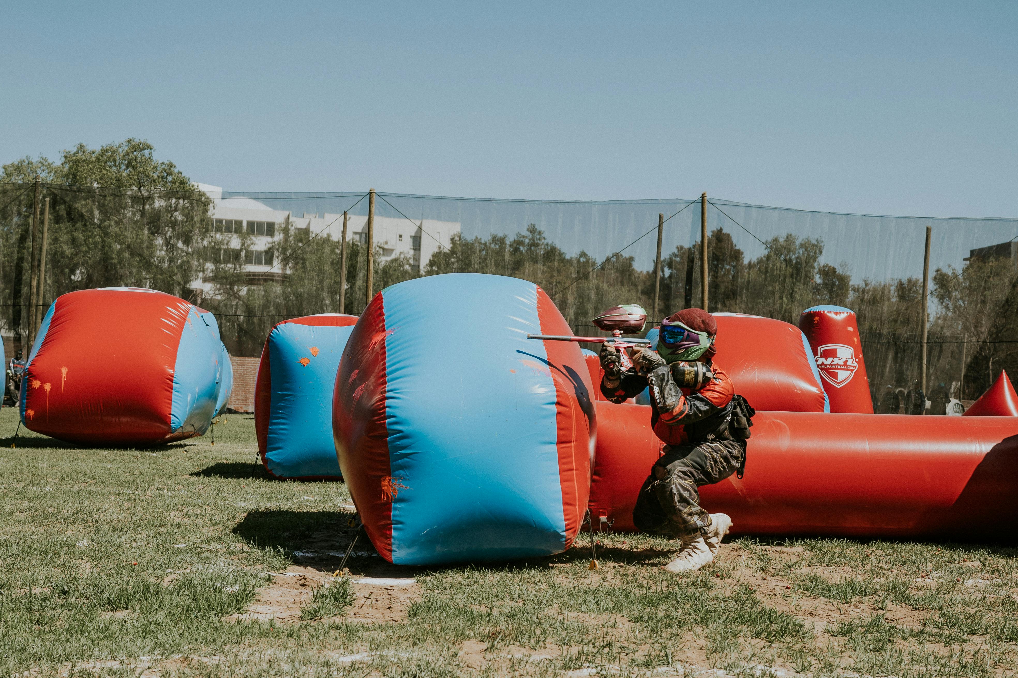 Un joueur de paintball se mettant à couvert derrière des obstacles gonflables lors d'une partie intense. Prescription Goggle Inserts - A paintball player taking cover behind inflatable obstacles during an intense game.