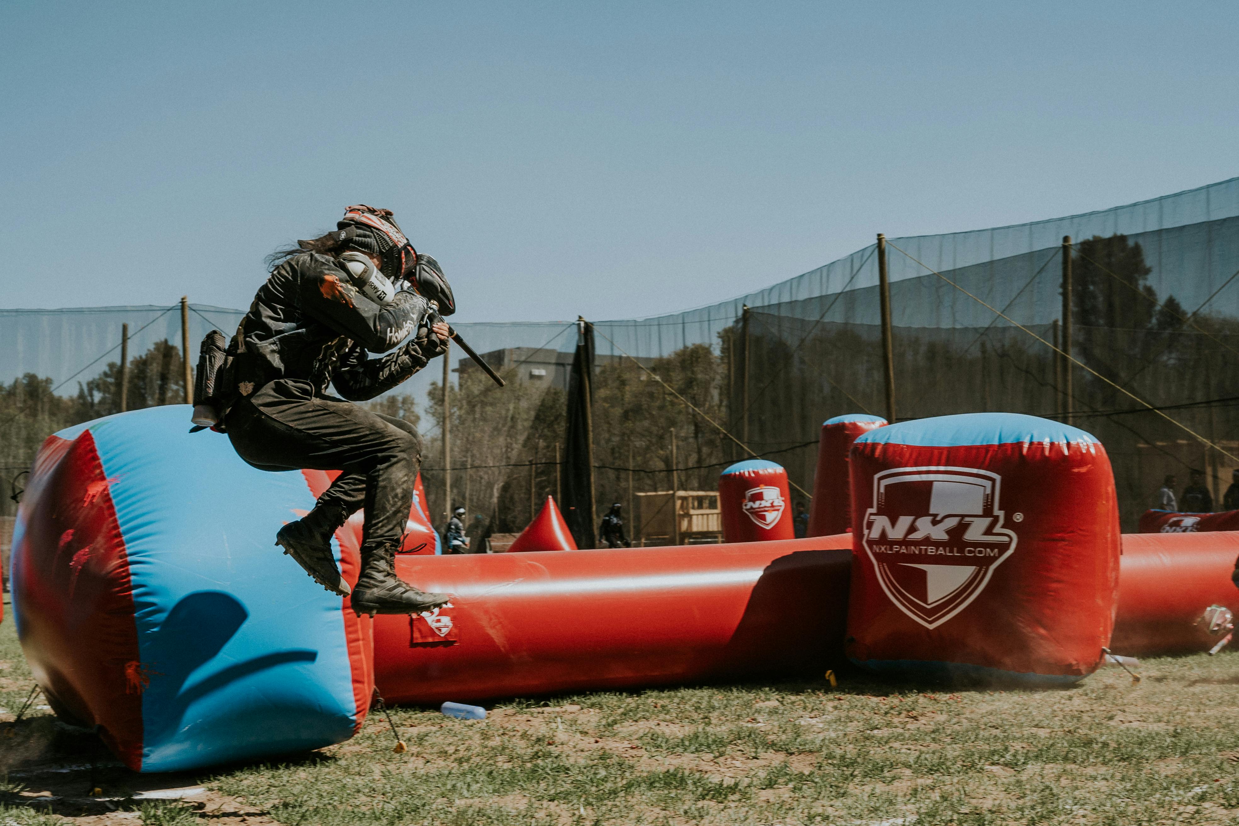 Dynamic paintball match action with player jumping over inflatable barriers in an outdoor field. Prescription Goggle Inserts - Dynamic paintball match action with player jumping over inflatable barriers in an outdoor field.