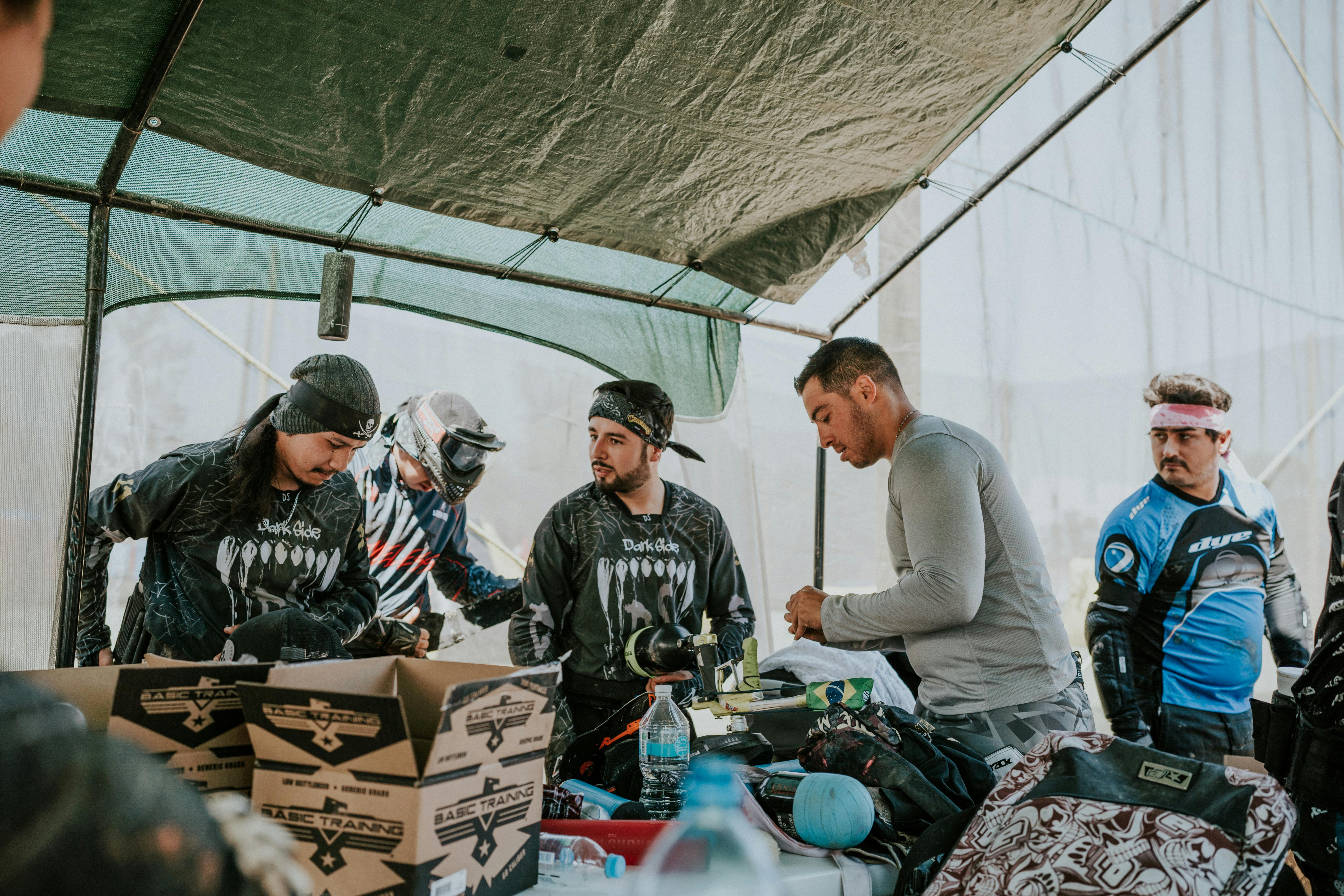 Men in paintball gear preparing for a game in an outdoor tent setting. Prescription Goggle Inserts - Men in paintball gear preparing for a game in an outdoor tent setting.