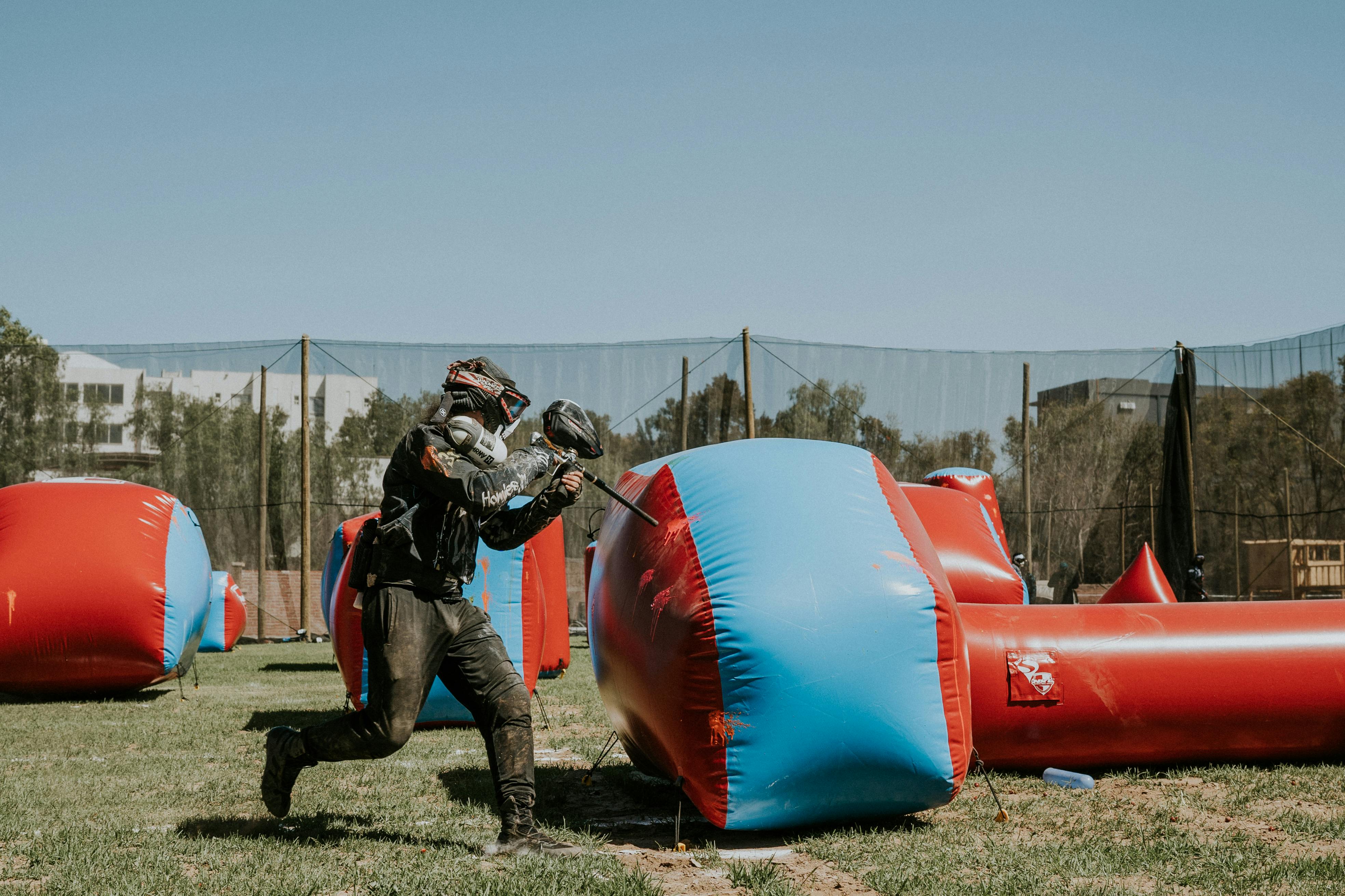 A player in action during an intense paintball game on a sunny outdoor field. Prescription Goggle Inserts - A player in action during an intense paintball game on a sunny outdoor field.