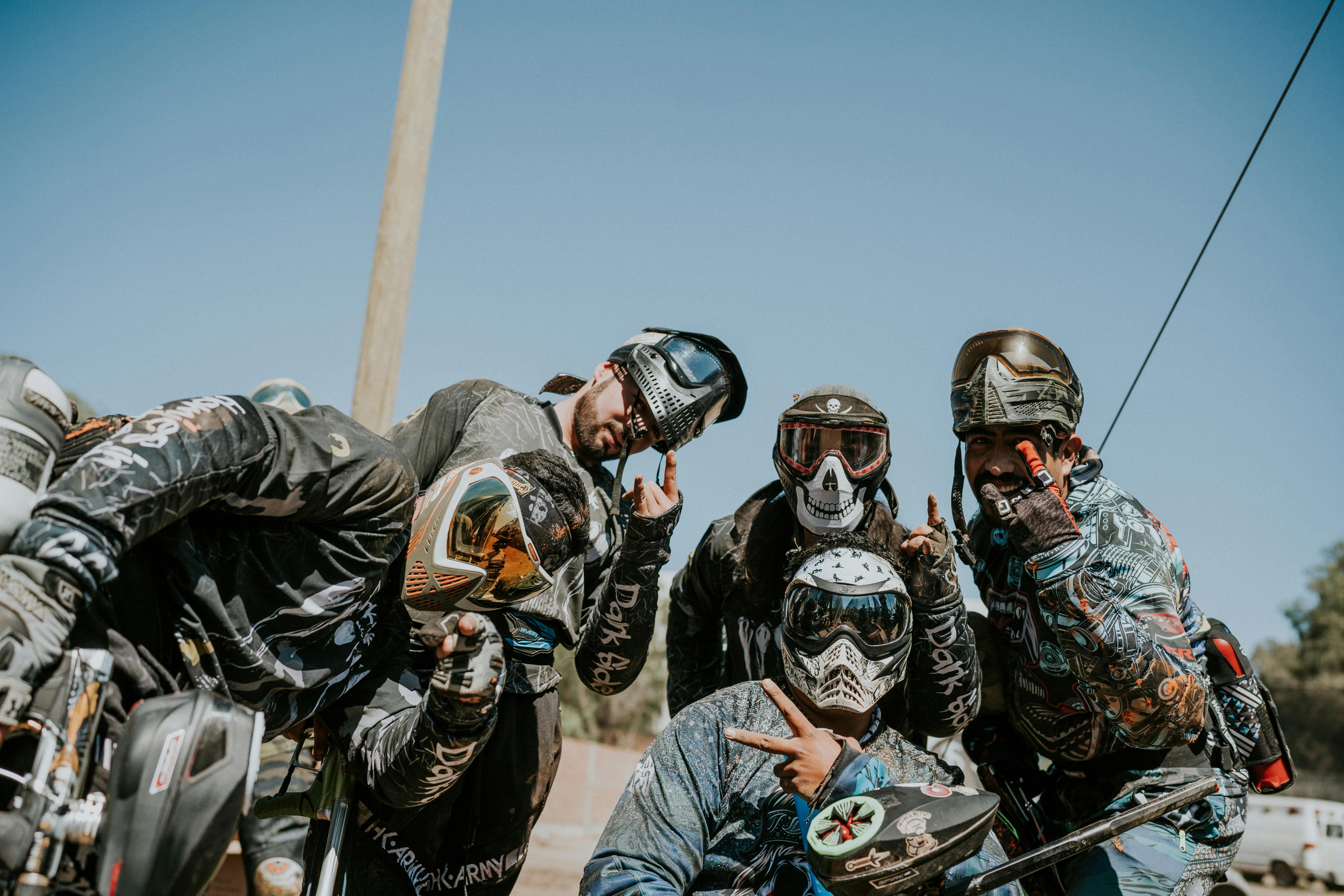 Five paintball players in gear, posing outdoors with hand gestures and goggles. Prescription Goggle Inserts - Five paintball players in gear, posing outdoors with hand gestures and goggles.