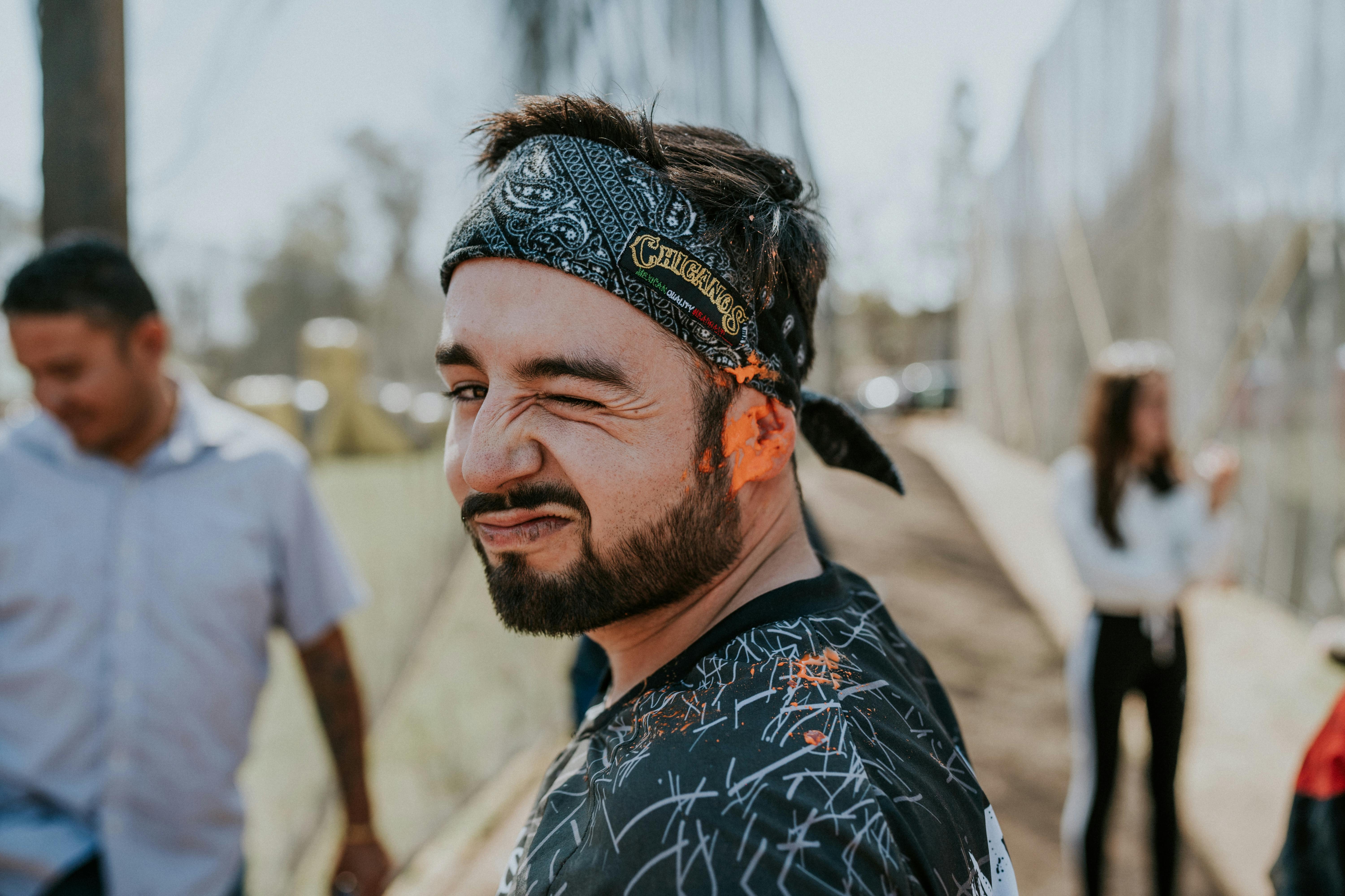 Man with paint-splashed face winking at an outdoor paintball event, embodying fun and adventure. Prescription Goggle Inserts - Man with paint-splashed face winking at an outdoor paintball event, embodying fun and adventure.