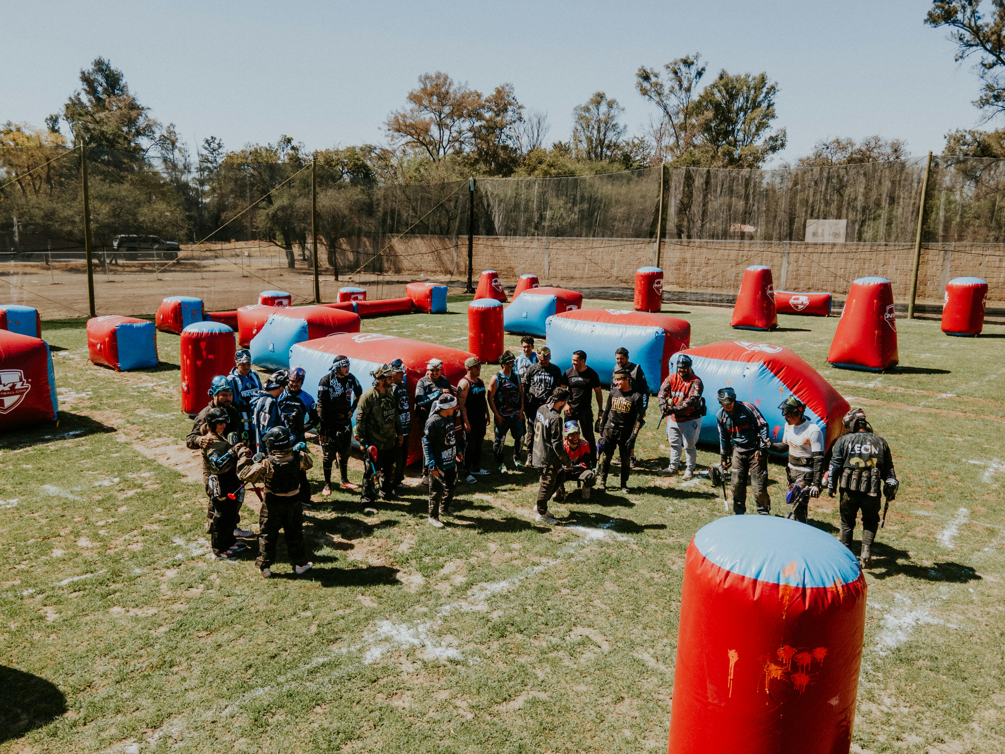 Un groupe jouant à un jeu de paintball intense en plein air à León, au Mexique, par une journée ensoleillée. Prescription Goggle Inserts - A group playing an intense outdoor paintball game in León, Mexico on a sunny day.