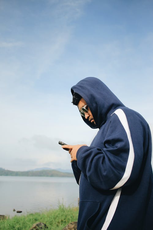 Man in Hoodie Standing with Cellphone