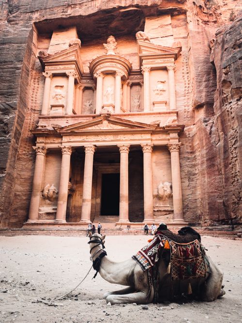 Free Explore the ancient Treasury in Petra with a camel resting in front, capturing history and adventure. Stock Photo
