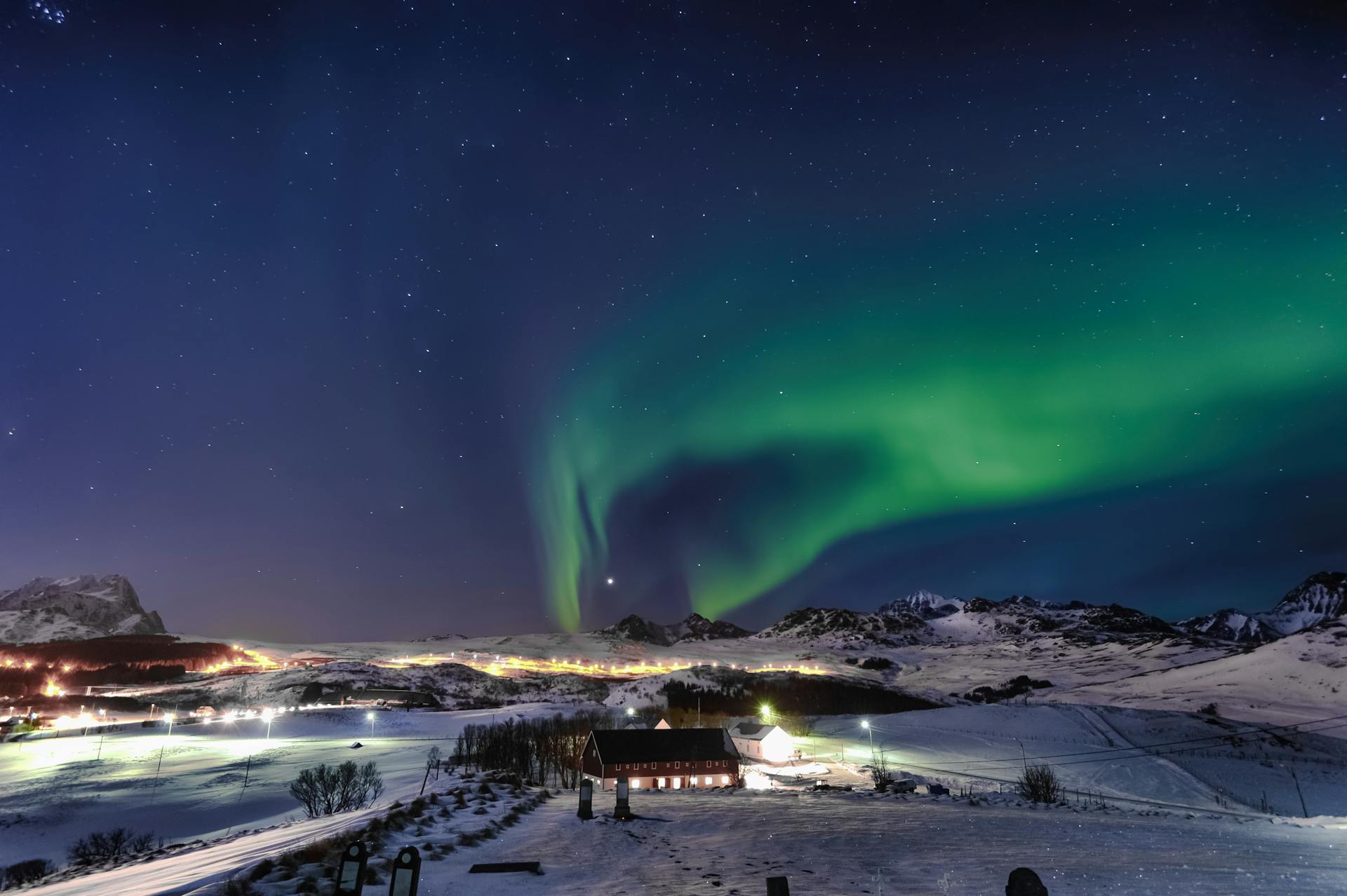 Stunning view of the aurora borealis illuminating the night sky in Norway, above a wintery landscape.
