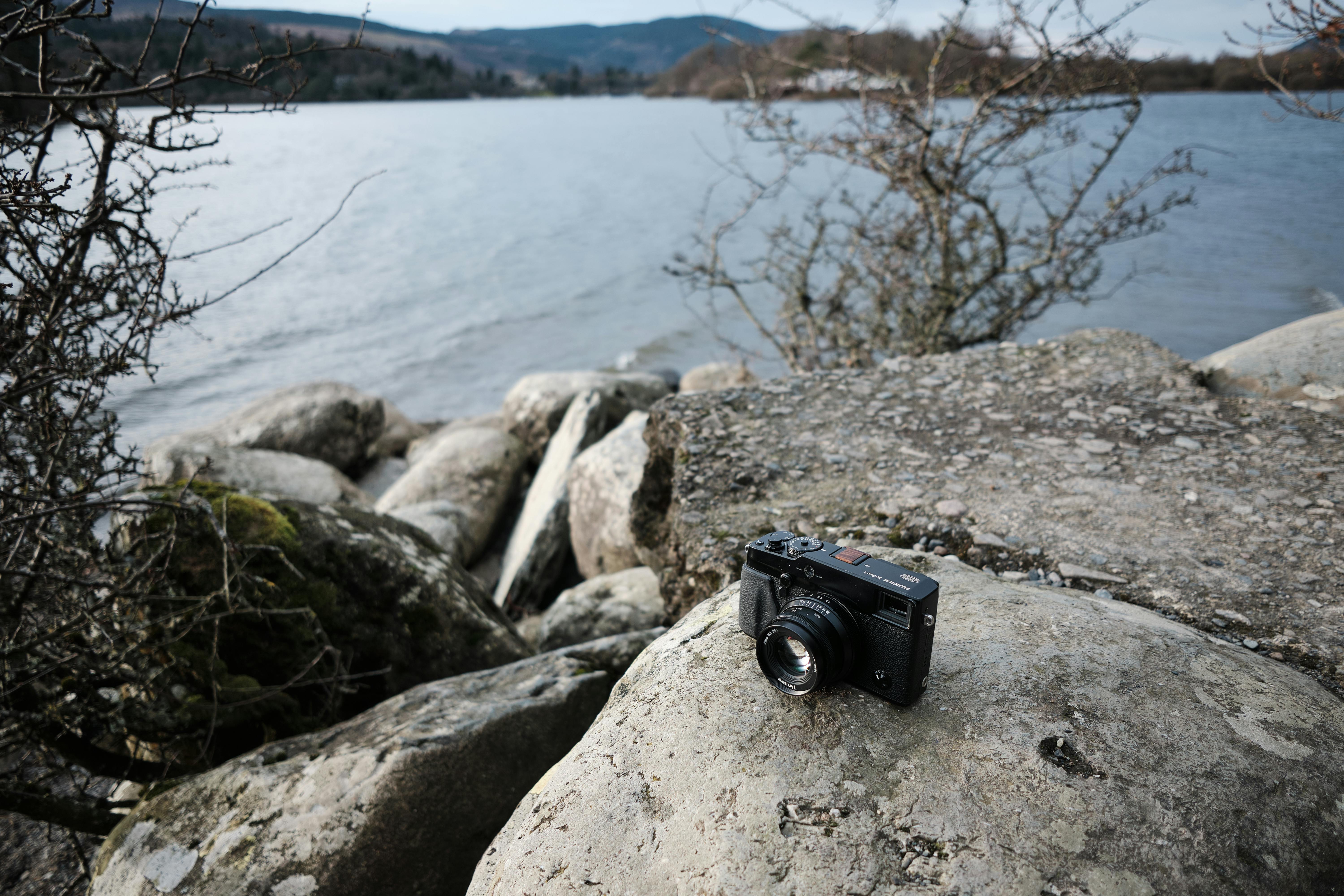 close up of a camera standing on a stone near a body of water
