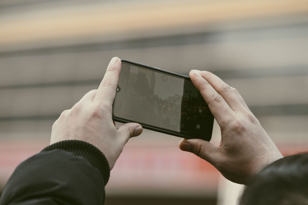 Close-up of hands using a smartphone to capture a photo outdoors