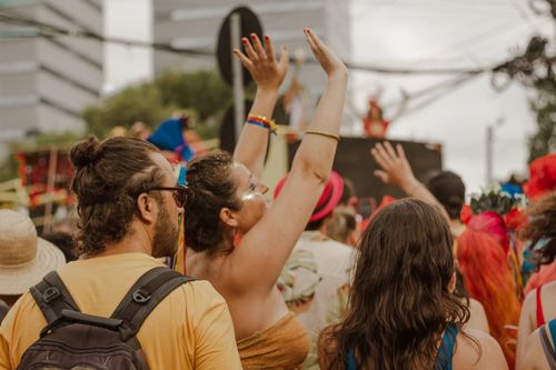 Free Vibrant outdoor festival with people celebrating and raising arms, creating a lively atmosphere. Stock Photo