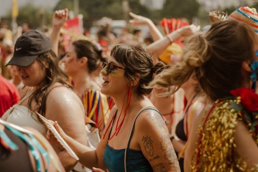Joyful crowd of women celebrating at a vibrant summer festival outdoors, full of colorful outfits and energy.
