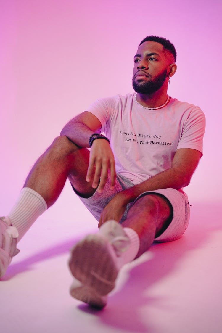 Young Man Sitting On Floor In Pink Studio