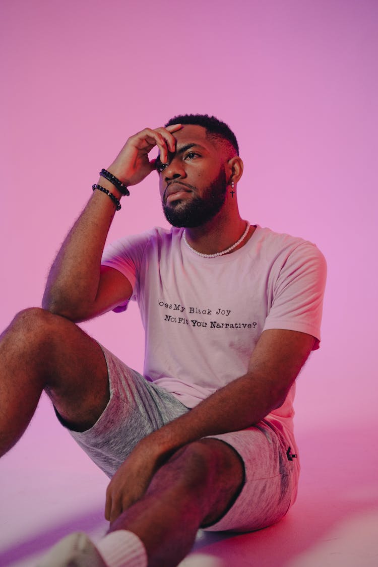 Young Man Sitting On Floor In Pink Studio