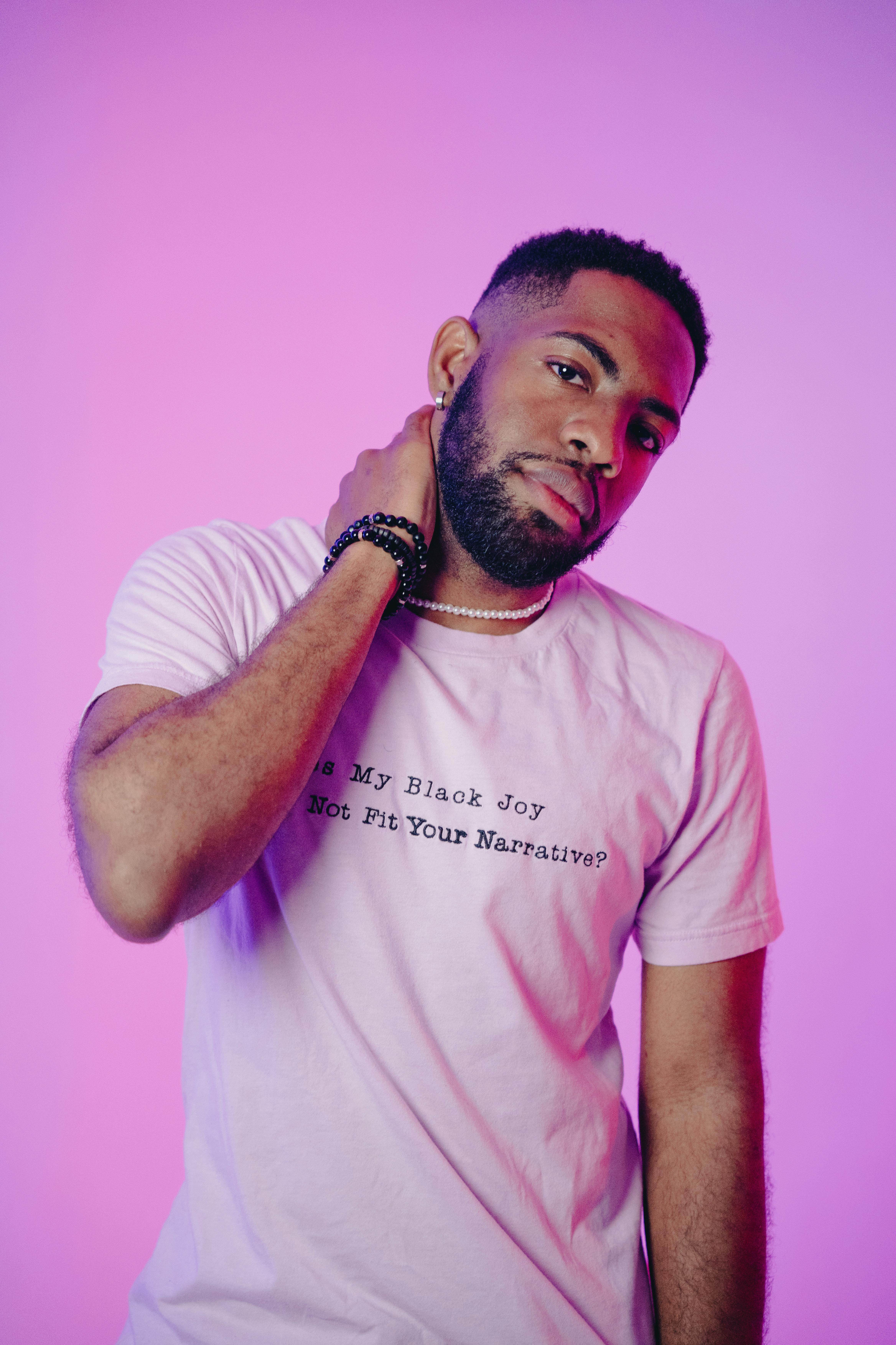 African American man with beard in a pink studio posing casually. Stylish and fashionable.