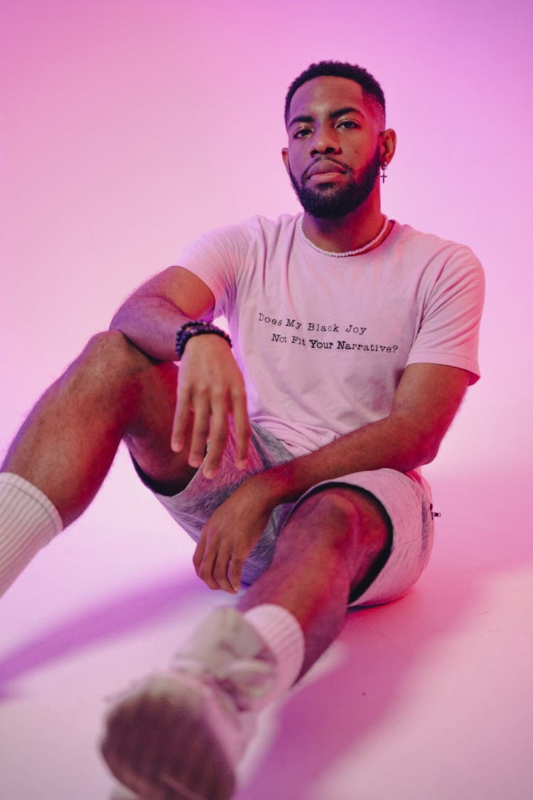 Young Man Sitting On Floor In Pink Studio