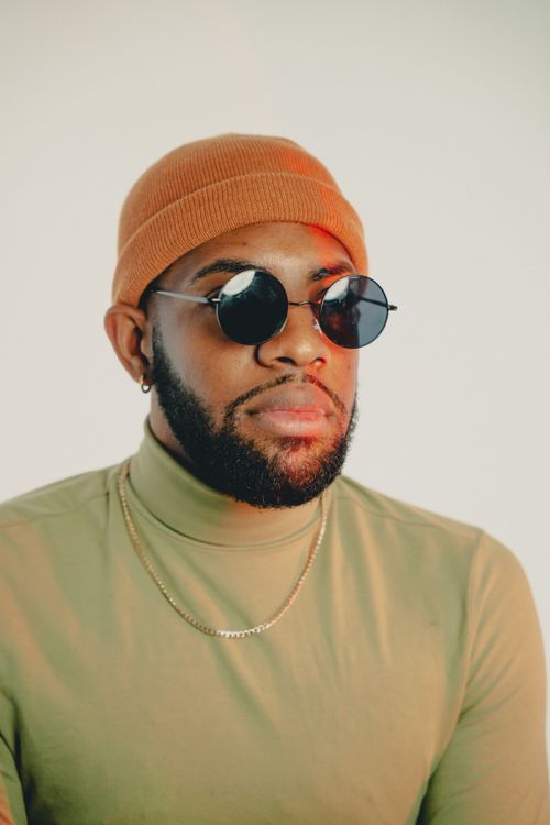 Free Stylish adult man wearing a beanie and sunglasses, showcasing modern fashion in a minimalist setting. Stock Photo