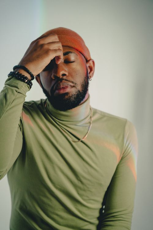 Free Artistic portrait of a fashionable man in a green turtleneck sweater, exuding a calm demeanor. Stock Photo