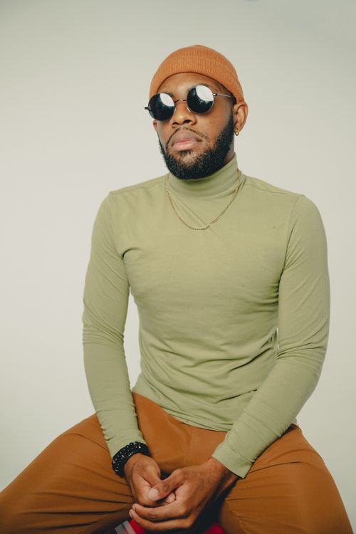 Free Fashionable man in sunglasses and beanie posing confidently against a plain backdrop. Stock Photo