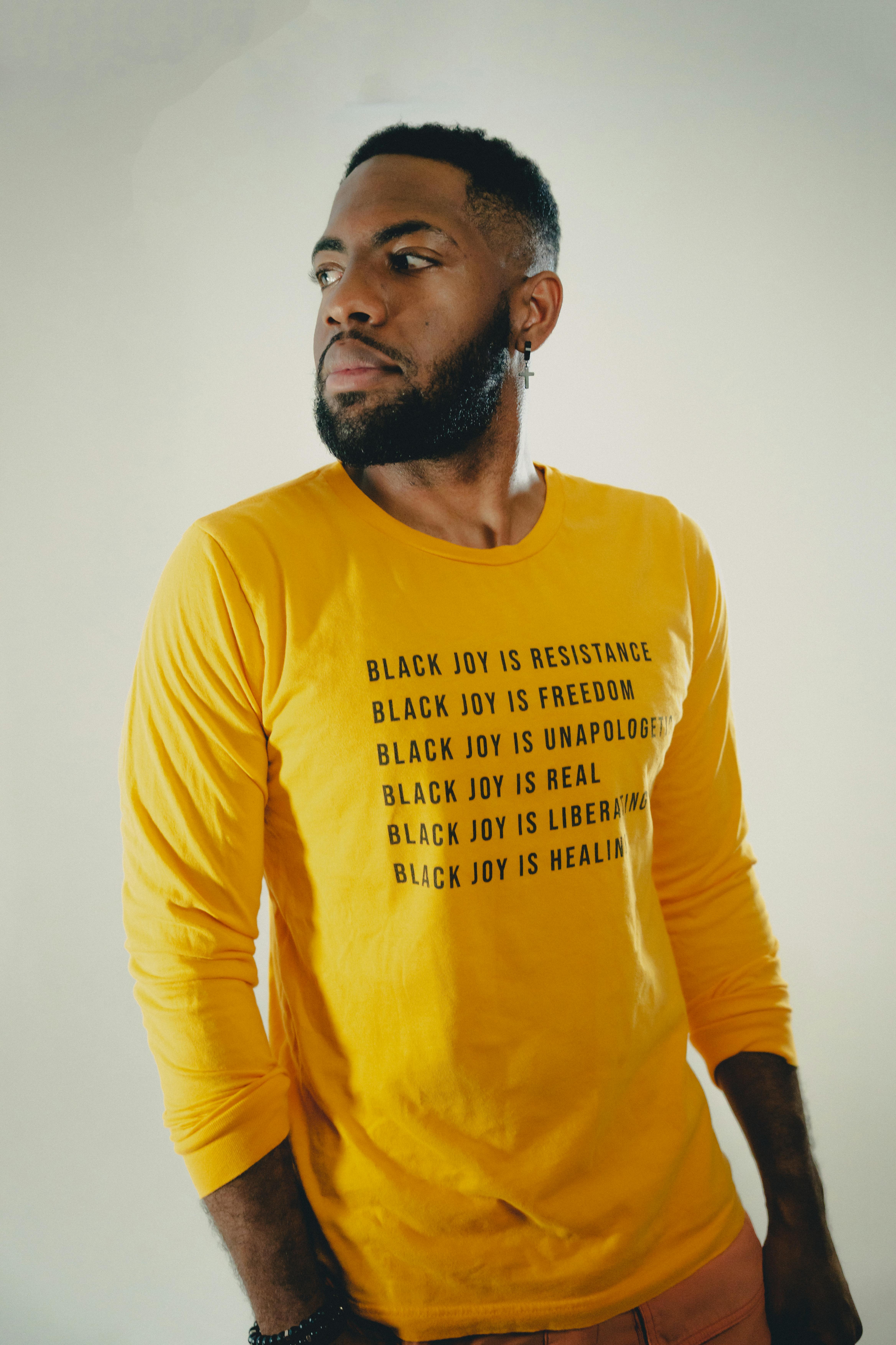 Studio portrait of a man in a yellow shirt with empowering messages about Black joy.