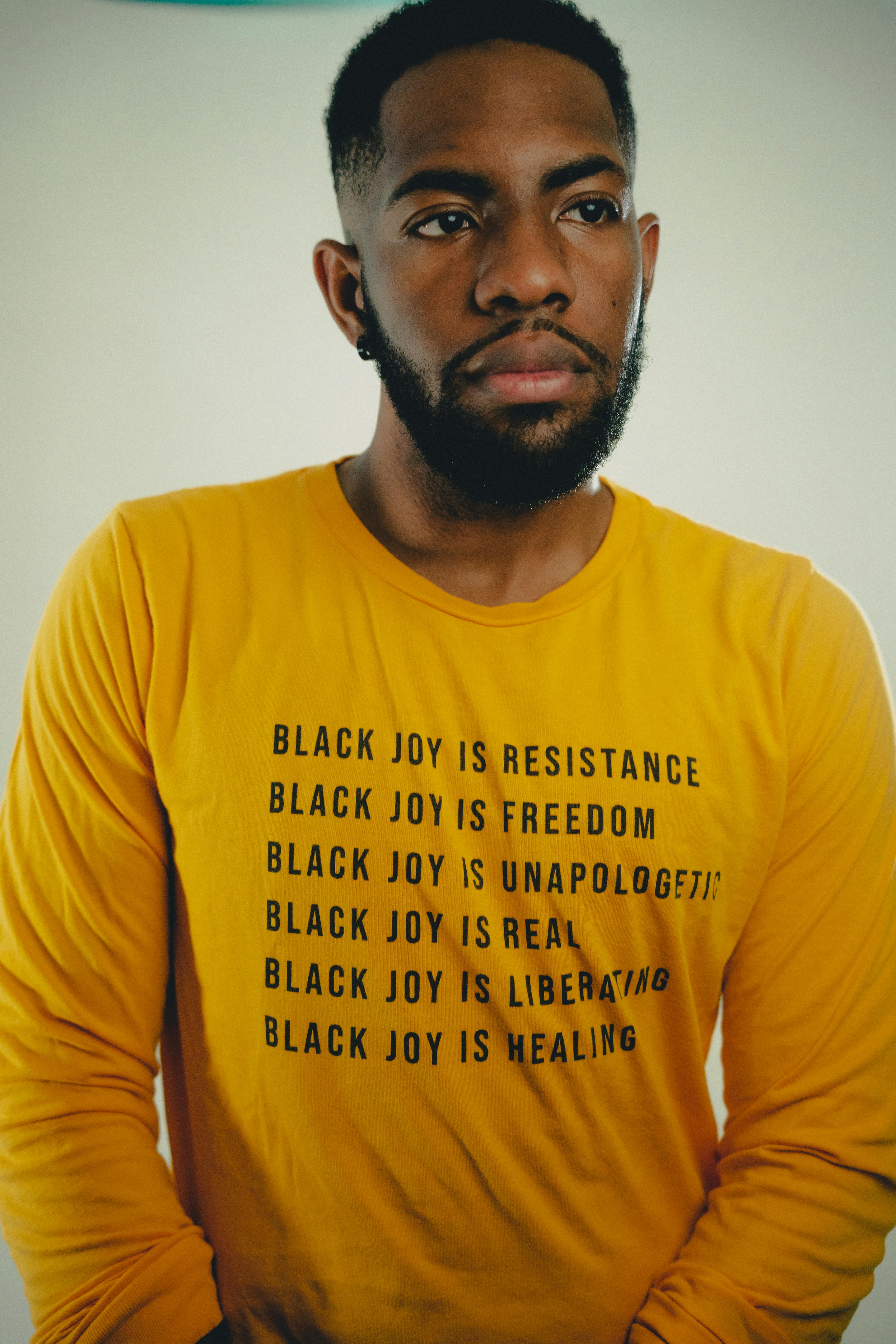Portrait of African American man wearing a yellow shirt with empowering messages about Black joy.