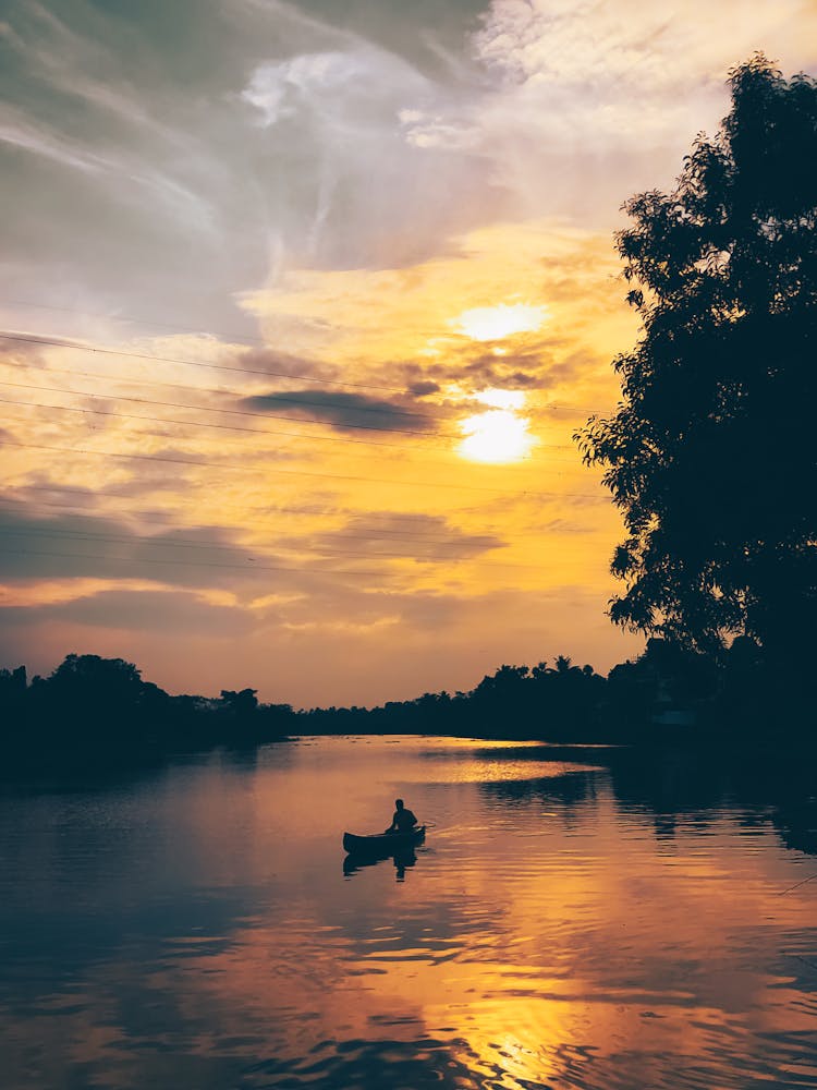 Silhouette Of A Person On A Boat During Golden Hour