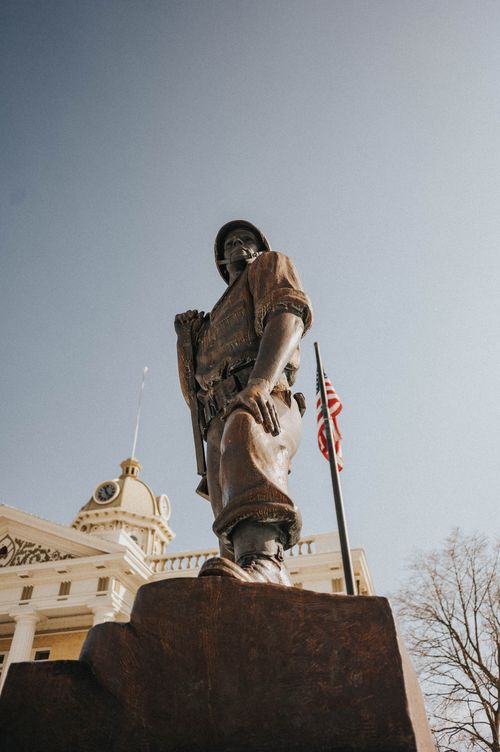 Free Low angle shot of a soldier statue with American flag, depicting patriotism in an urban setting. Stock Photo