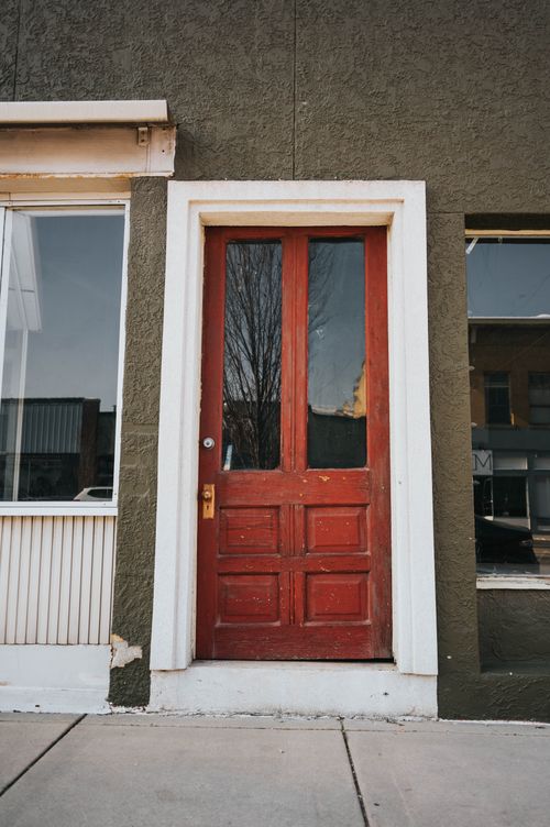 Free Close-up of a red wooden door on an urban city street facade. Stock Photo