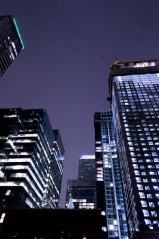 City skyscrapers with illuminated windows at night showcasing modern architecture.