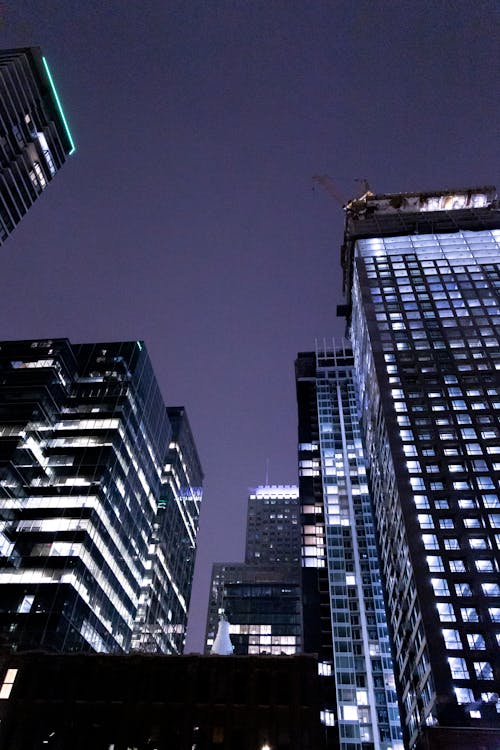 Free Low Angle Shot of Illuminated Skyscrapers in City at Night  Stock Photo