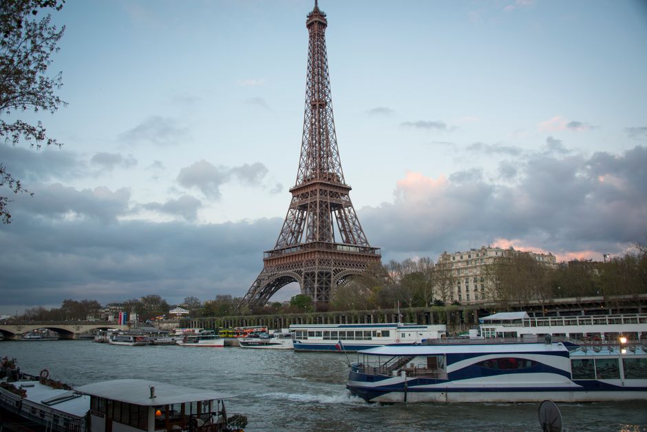 Scenic view of the Eiffel Tower during sunset with boats on the Seine River.